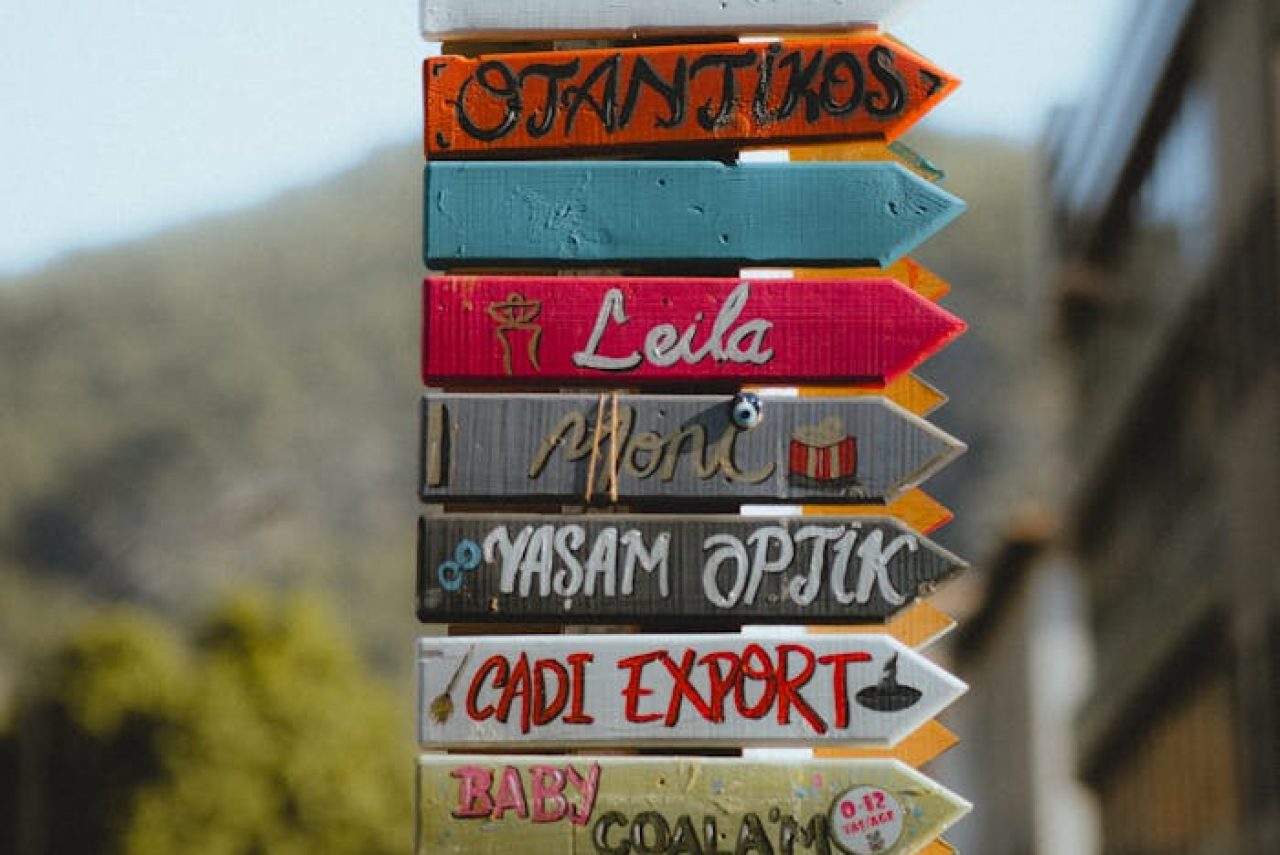 Vertical shot of colorful directional signs on a street pole with selective focus.